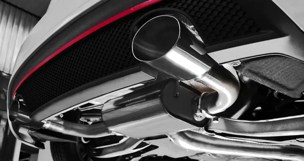 Unterbodenansicht: polierte Sportauspuffanlage mit Endrohr und Schalldämpfer unter dem Fahrzeugheck; rote Zierlinie am Heckdiffusor.